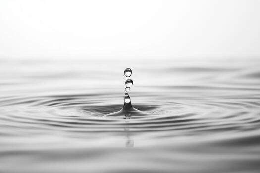 Water droplet creates ripples in calm water surface during midday photo
