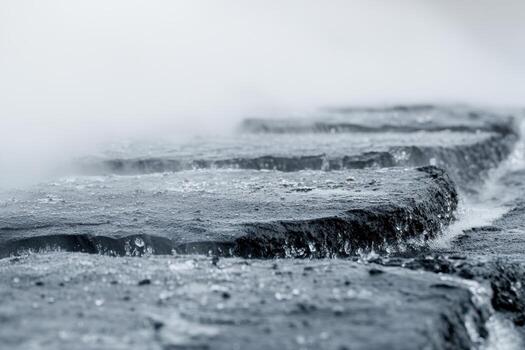 Flowing water over smooth stones in a misty setting at sunrise photo