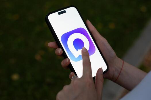 Moscow, Russia, August 14, 2025. Hand holding smartphone displaying logo of Russian messaging app Max. User is tapping screen, emphasizing app accessibility and user interaction photo