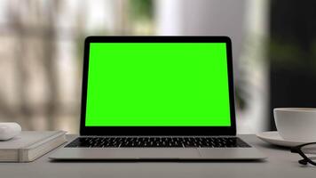 schermo verde Schermo su il computer portatile impostato su bianca tavolo. sfocato casa ufficio spazio di lavoro. croma chiave su schermo per chiamata, sito web modello presentazione gioco applicazioni. libero professionista attività commerciale. Ingrandisci nel video