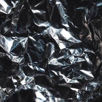 Metallic foil appears strikingly wrinkled and reflects light, creating dynamic patterns and textures photo