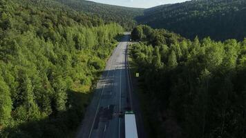 Drohne Antenne Aussicht von ein Berg Autobahn umgeben durch dicht Grün Wald, mit ein LKW Fahren entlang das Straße auf ein sonnig Tag. August 2, 2025. Republik von Baschkortostan, Russland video