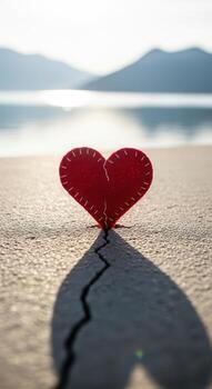 Red felt heart on cracked ground with shadow and mountains photo