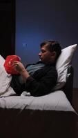 un hombre tendido en cama con un rojo corazón monitor video