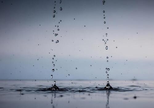 Close-up of water droplets splashing on a calm surface, creating ripples against a serene backdrop photo