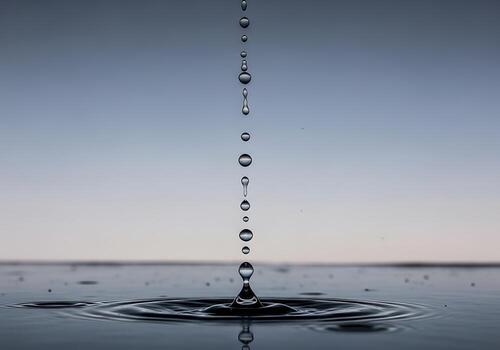Water droplets falling from above, creating ripples on a calm surface with a serene sky backdrop photo