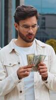 glücklich jung indisch Mann Zählen Geld Kasse halten Dollar Banknoten, Rechnungen Budget Anzahl Gehalt profitieren Belohnung bestechen draußen. erfolgreich Reich arabisch Hindu Kerl im Innenstadt Stadt Straße. Geschäft Menschen video