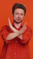 sluta, tillräckligt. caucasian man säga Nej håll handflatan vikta korsade händer i Avsluta gest, varning av Avsluta, förbjuden tillgång, minskande kommunikation, kropp språk fara. ung kille på orange bakgrund video