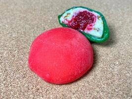 Red mochi daifuku with berry filling on cork background, Japanese dessert close up with copy space photo