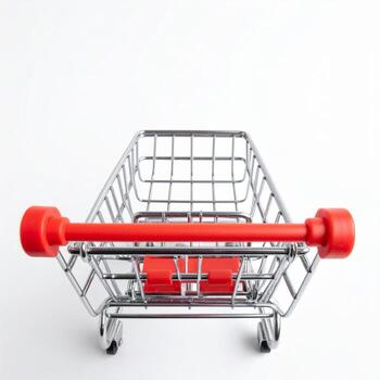 A miniature shopping cart with a red handle sits on a white surface, top front view, isolated on white background. photo