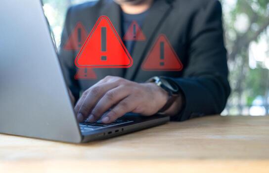 Businessman using laptop with spam virus with warning to alert internet security and data breach or hacker or spyware. photo