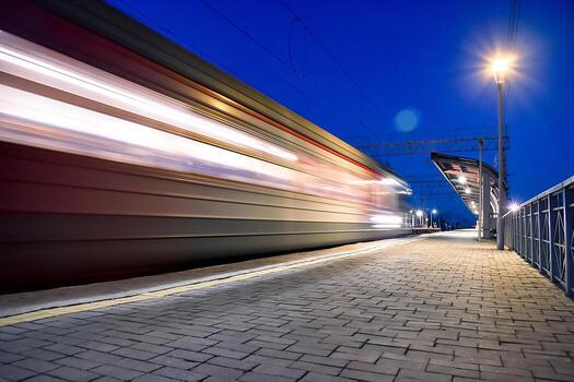 Evening arrival of the train on an empty platform. . Photo taken with a shutter speed. Rays of light. Blur. Evening railway station.