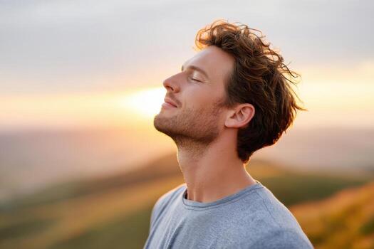 Man practicing deep breathing on top of a hill, enjoying the serene sunset view, surrounded by nature, promoting relaxation and mindfulness in a tranquil environment photo
