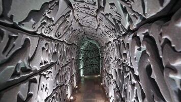 invecklad sten tunnel med texturerad väggar upplyst förbi mjuk belysning, visa upp de gradvis övergång av ljus och skugga i en fängslande arkitektonisk Plats video