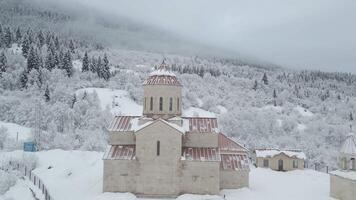 georgiano ortodoxo Iglesia rodeado por invierno bosque y cubierto de nieve montañas en svaneti región de Georgia. video