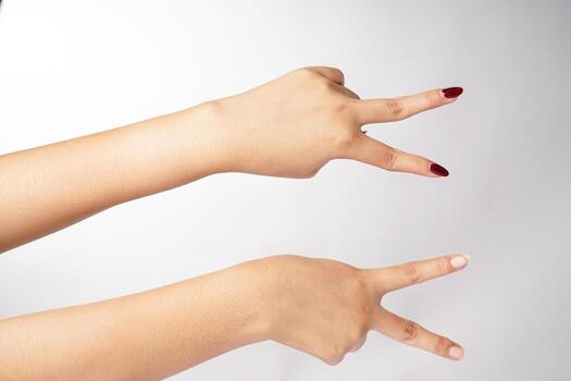 Two hands are shown making a V gesture turned to the side in front of a plain white background photo
