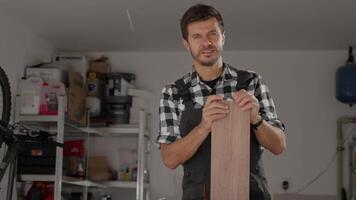 snickare stående i Hem verkstad med trä- panel och verktyg på arbetsbänk. porträtt av små företag ägare i garage. begrepp av träbearbetning och beställnings- möbel framställning video