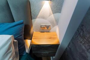 un mesita de noche ese es situado en un acogedor dormitorio, adornado con un lámpara Proporcionar suave iluminación en sus superficie, creando un calentar y atractivo atmósfera Perfecto para relajación foto