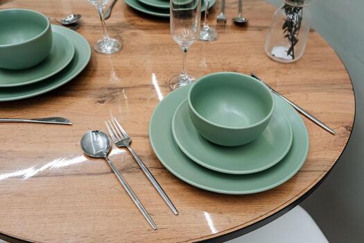 This is an elegant dining setting that features beautiful green tableware, complemented by a chic and stylish wooden table, creating a perfect ambiance for gatherings and meals photo