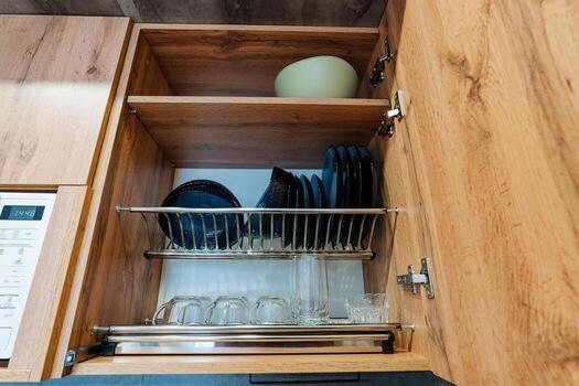 The kitchen cabinet is filled with an array of plates, several glasses, and a beautiful bowl, all neatly arranged within it, showcasing an organized and functional kitchen space photo