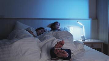 asiático soltero mamá es insomne, inquieto pierna síndrome, es estresado, preocupado, despierto a noche cerca su niño, con insomnio enfermedad, y menopáusico mujer, familia cuidado de la salud problema. video