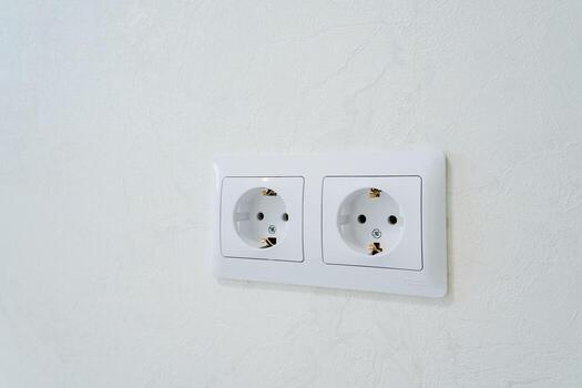 There are two white electrical outlets that have been strategically installed on a clean, white wall for efficient use. These outlets provide necessary access to electrical power photo