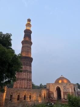 Distant view of Qutub Minar surrounded by lush greenery and cloudy sky, Delhi, India photo