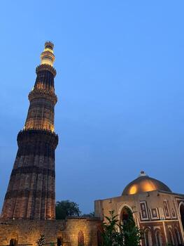 Qutub Minar at twilight with clear blue sky, illuminated ancient monument in Delhi photo