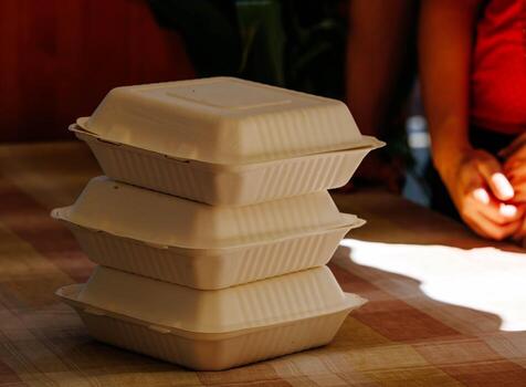 Stack of three eco-friendly biodegradable takeout containers on table with blurred background photo