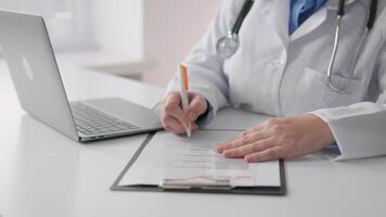 en sjukvård professionell i en labb täcka är slutföra patient dokumentation på en Urklipp medan använder sig av en bärbar dator för digital uppgifter, visa upp de blandning av traditionell och modern medicin. video