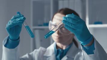 een geschoold wetenschapper is evalueren twee complex chemisch oplossingen in test buizen, gebruik makend van Geavanceerd laboratorium technieken in een modern Onderzoek milieu voor wetenschappelijk ontdekking en innovatie video