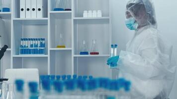 im ein modern Labor ausgestattet mit Glaswaren und Experimental- Setups, ein gewidmet Wissenschaftler im ein schützend passen untersucht Proben und betreibt ein Hightech Mikroskop zum Forschung video