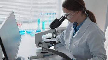 In a modern lab, a researcher examines samples under a microscope while reviewing extensive data on a computer, emphasizing the crucial connection between science and technology in their work video