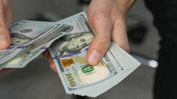 An extremely detailed and closeup view of a pair of hands meticulously counting a stack of crisp hundred dollar bills, vividly showcasing various money transactions and intricate financial exchanges video