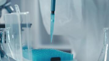 i en labb, en skicklig forskare användningar en pipett till klara av en vibrerande blå flytande, highlighting de nödvändighet av precision och noggrannhet i vetenskaplig forskning och innovation för framåt olika fält video