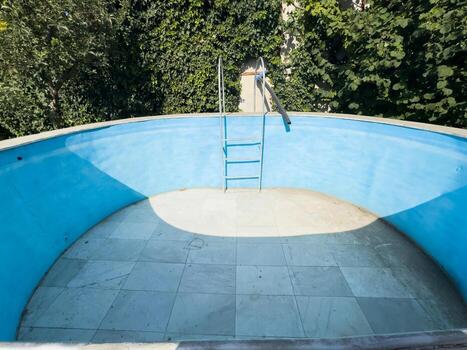 Old empty swimming pool with blue walls. Pool without water, dried up pool photo
