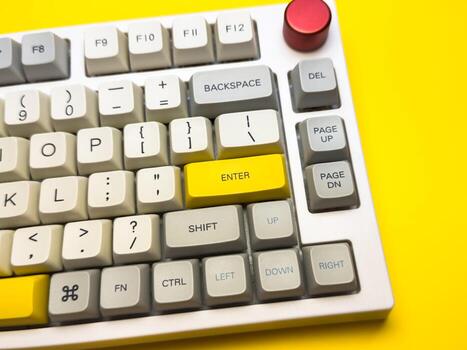 White office keyboard with bright Enter key on bright yellow background, minimalism, keyboard buttons. A keyboard with a yellow key on the bottom left photo