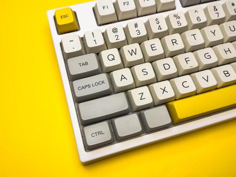 Close up White mechanical keyboard with bright Esc key on bright yellow background, minimalism, keyboard buttons. A keyboard with a yellow key on the bottom left photo