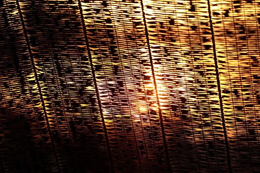 Golden sunlight shining through woven texture pattern creating abstract background photo