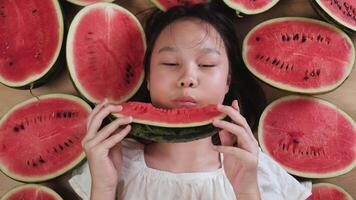 Asian young teenage girl eating many half pieces of fresh red watermelons, enjoying biting watermelon slices, healthy eating, abundant fruit, happiness, and hot summertime. video