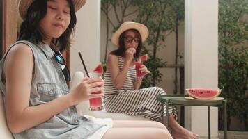 Happiness Asian family vacation, girl with casual hat and mum enjoy drinking fresh watermelon smoothies, and cheerful relaxing on holidays with parent in hot summertime at outdoor terrace. video