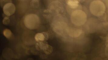 sognante d'oro bokeh luci scintillante dolcemente nel il scuro, Perfetto per la creazione di magico sfondi video