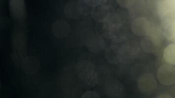 etherisch glinsterende licht bokeh Aan donker oppervlakte creëert een humeurig en boeiend abstract achtergrond video