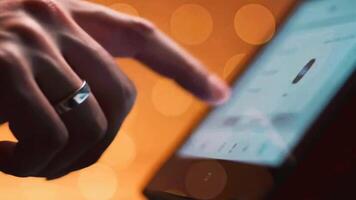 Close up of a finger scrolling on a tablet or smartphone touch screen. A person browsing the internet or using an app with a warm bokeh background. video