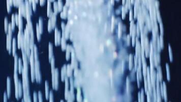 långsam rörelse makro av luft bubblor stigande i klar blå vatten mot en mörk bakgrund skapande en färsk abstrakt effekt video