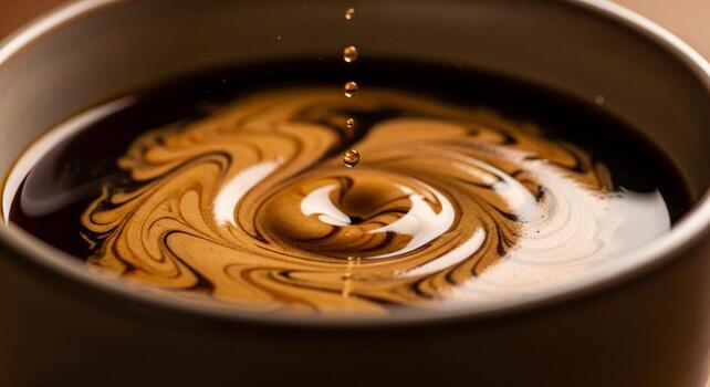 Close up of cream swirling into dark coffee creating a mesmerizing vortex pattern in a mug photo