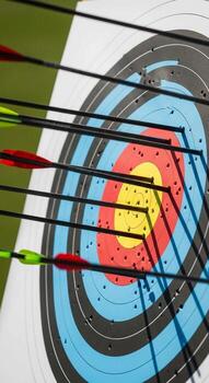 Archery arrows fletched in red and green pierce a colorful target with precision and focus on a sunny day photo