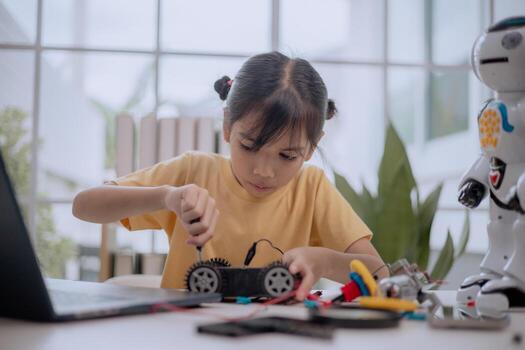Asian girl assembling robot car with screwdriver, learning STEM education and robotics engineering. Concept of child creativity, innovation, future technology skills and digital learning at home. photo