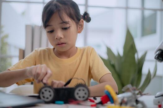 Asian girl building robot car with screwdriver, learning STEM education and robotics engineering. Concept of child creativity, innovation, digital learning, future skills and technology development. photo