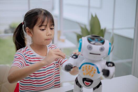 Asian girl assembling toy robot with screwdriver, learning STEM education and robotics engineering. Concept of child creativity, innovation, technology skills and future digital learning. photo